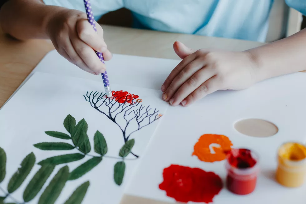 close-up-boy-siting-desk-drawing-rowanberries-album-sheet-with-dry-rowan-leaves