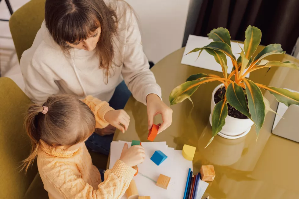 mom-is-playing-with-her-daughter-mom-little-girl-built-tower-colored-blocks