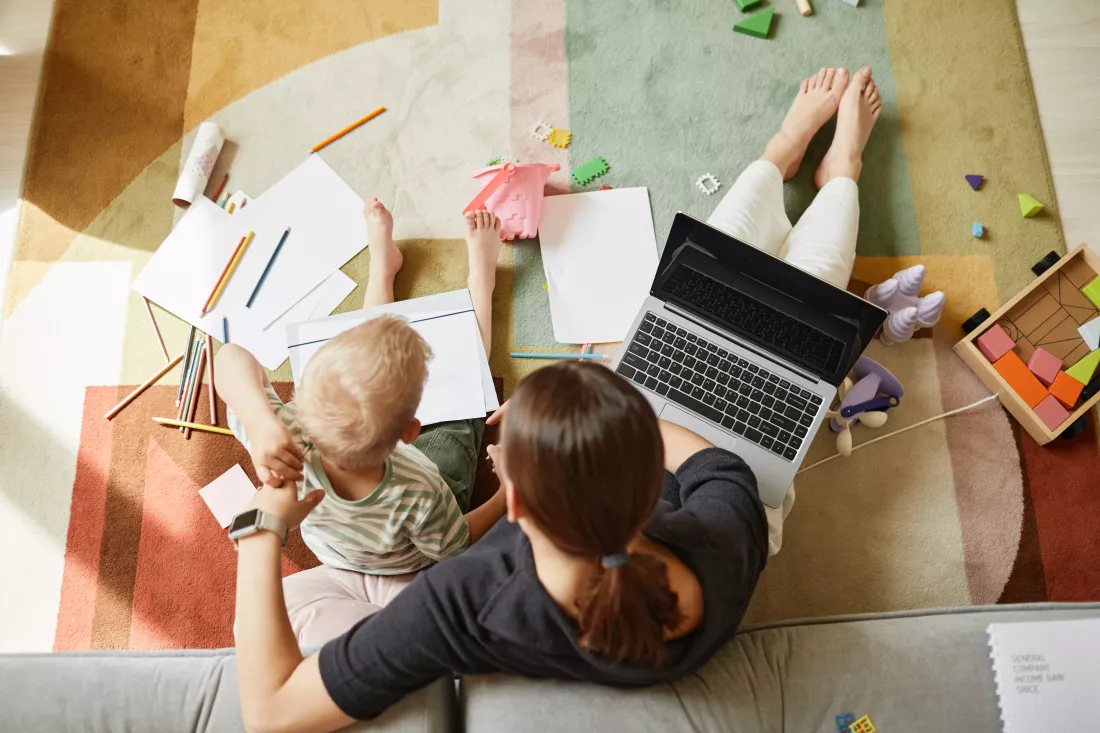 directly-view-multitasking-mother-sitting-floor-while-working-drawing-with-son-same-time