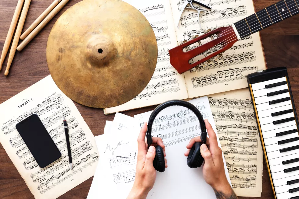 musical-setup-with-sheet-music-guitar-cymbal-keyboard-hands-holding-headphones-instruments-sheet-music-create-musical-atmosphere