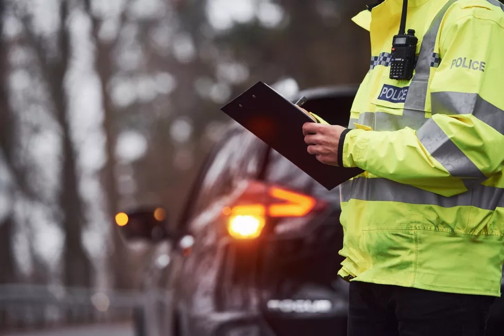male-police-officer-green-uniform-standing-with-notepad-near-car