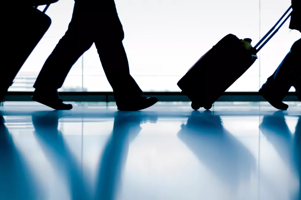 person-is-walking-with-suitcase-blue-surface