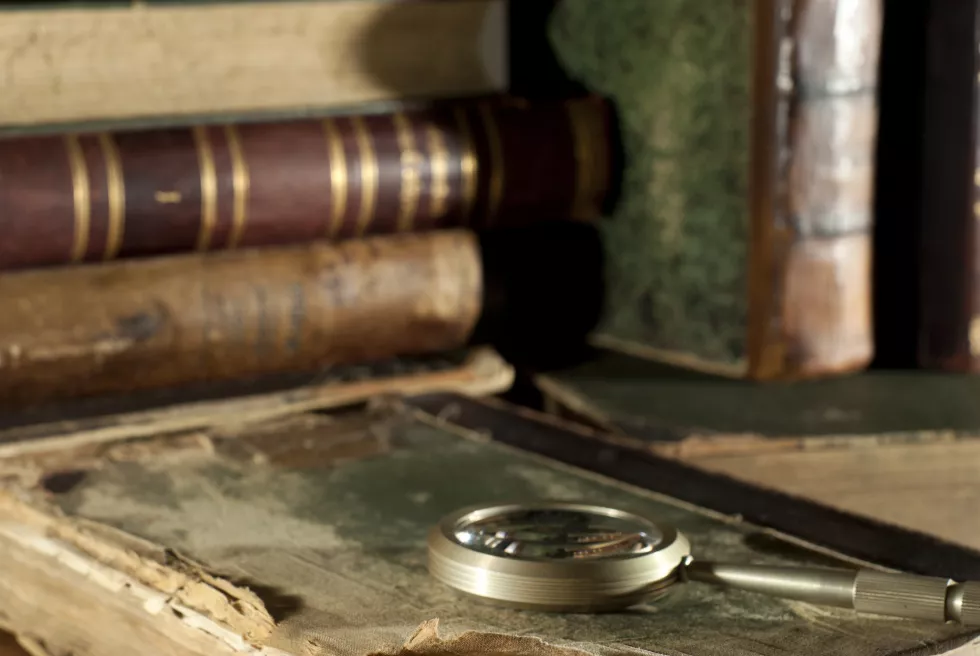 ancient-book-ragged-cover-magnifying-glass-table