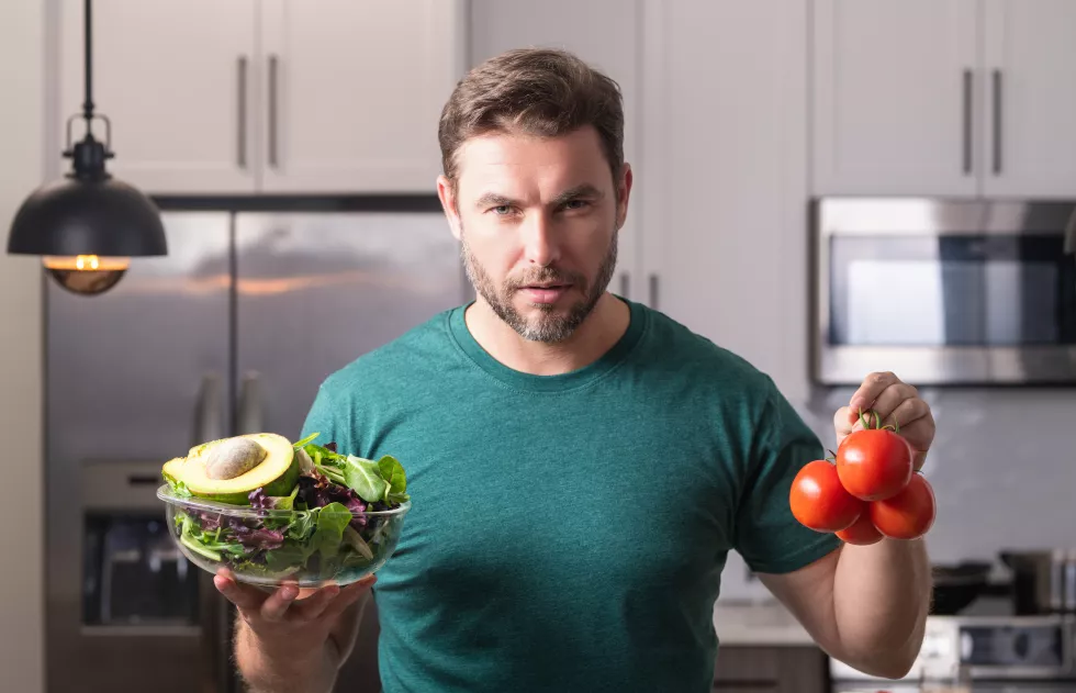 young-man-cooking-vegan-healthy-salad-kitchen-millennial-man-modern-kitchen-table-chop-vegetab