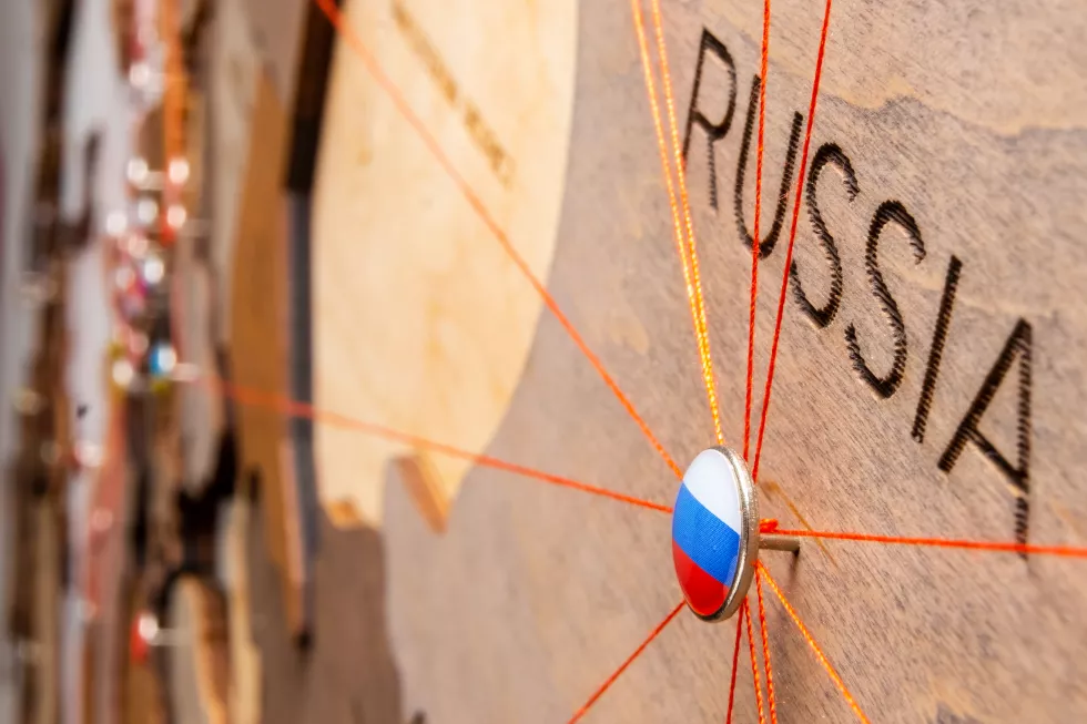 russia-flag-pushpin-red-threads-wooden-map-travel-logistic-routes-influence