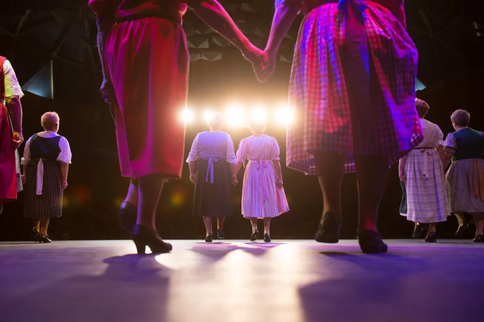 rear-view-women-holding-hands-while-standing-stage