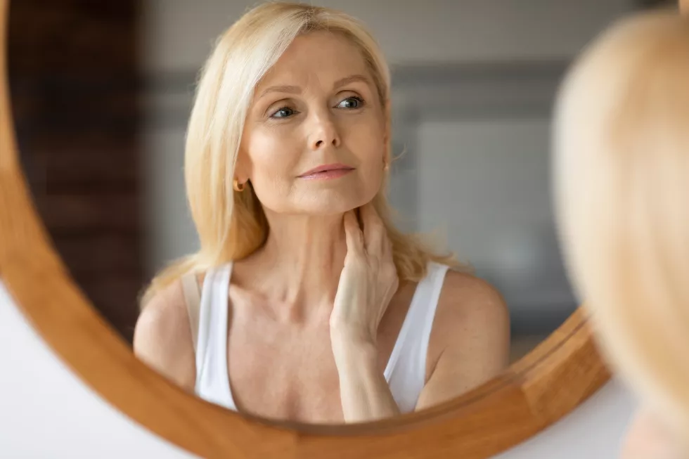 beautiful-aged-european-woman-touching-neck-looking-mirror-making-antiaging-beauty-routine