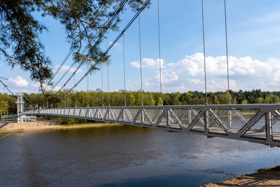 side-view-pedestrian-suspension-bridge-with-metal-railings-calm-river-leading