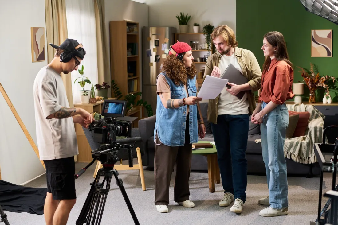 Młoda ekipa filmowa omawia scenariusz na planie zdjęciowym