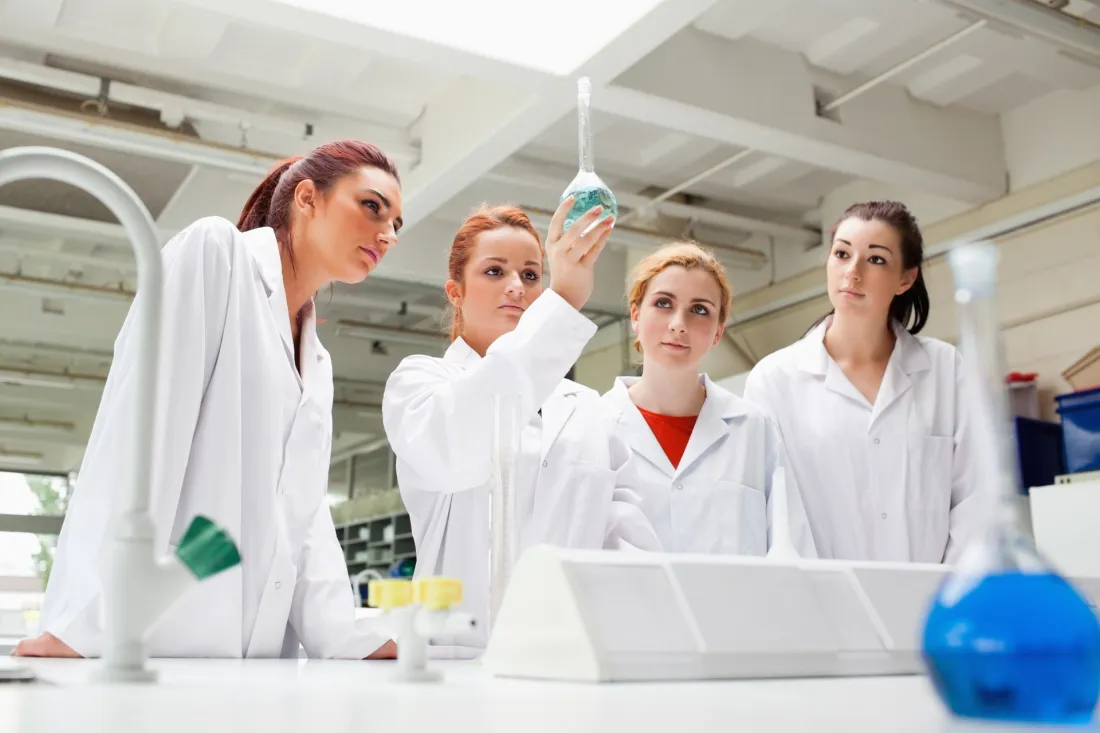 Studentki chemii oglądają roztwór w kolbie w laboratorium